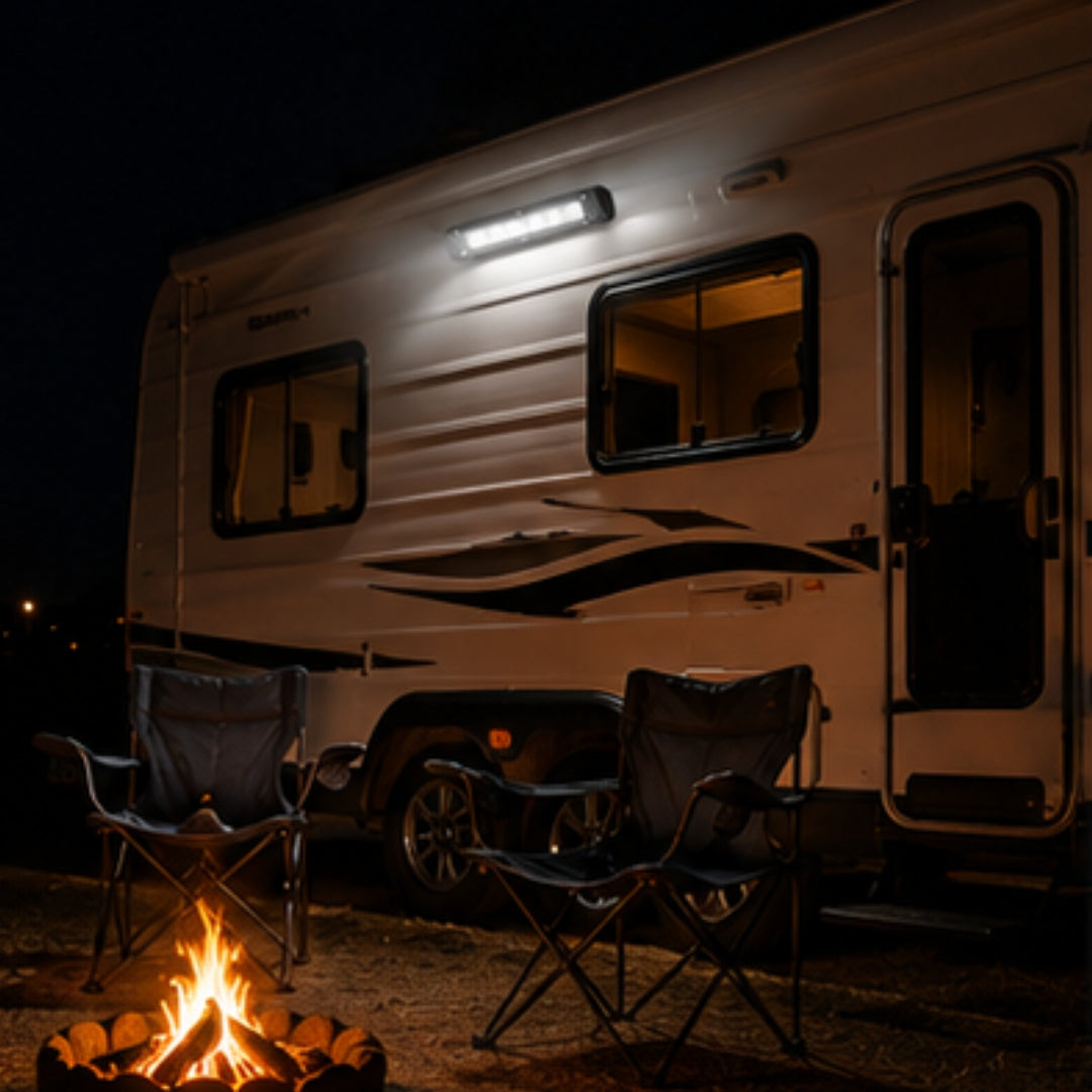 RV parked at night with two camp chairs around a fire pit.
