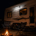 RV parked at night with two camp chairs around a fire pit.