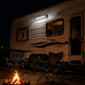 RV parked at night with two camp chairs around a fire pit.