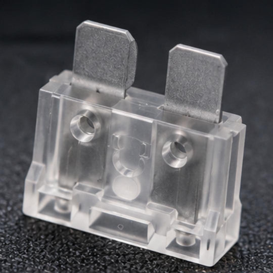 Clear plastic electrical component with metal contacts on a dark background