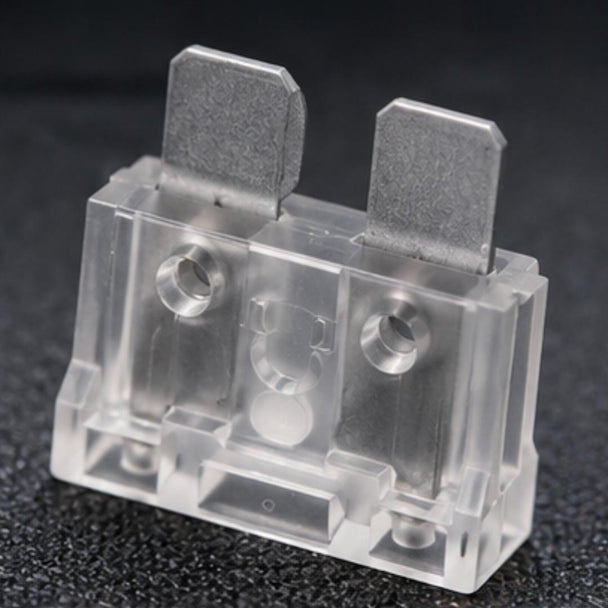 Clear plastic electrical component with metal contacts on a dark background
