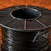 Spool of black wire on a wooden surface