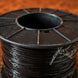 Spool of black wire on a wooden surface