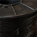 Close-up of a spool of black thread on a dark surface