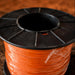 Spool of orange wire on a wooden surface
