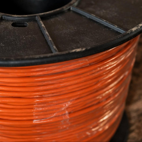 Close-up of a spool of orange cable with a black reel.