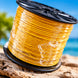 Spool of yellow cable on a wooden surface with a blurred natural background