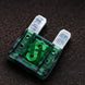 Green automotive fuse on a dark textured background