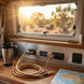 Interior of a vehicle with power outlets, a map, and a thermos near a window showing a scenic view.