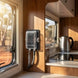 Power outlet on a wall inside an RV with a view of trees outside the window.