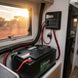 Lithium battery in a vehicle with wiring and control panel visible, window showing outdoor scenery.