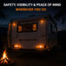 Camper van with lights on at night near a campfire, with text about safety, visibility, and peace of mind.