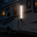 Lighted RV exterior with a prominent light fixture in the dark.