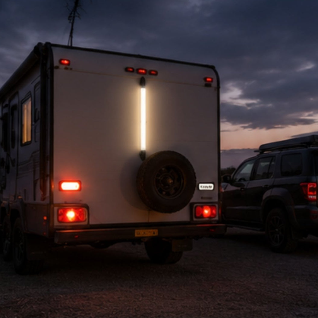 Back view of a camper trailer with visible lights against a dark sky.