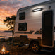 Camper trailer parked by a campfire with a sunset over water