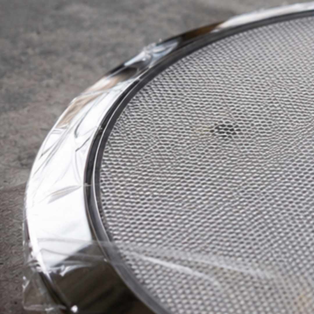 Close-up of a metal strainer with a textured surface on a gray background