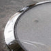 Close-up of a metal strainer with a textured surface on a gray background