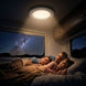 Family lying in bed under a night sky view with a light fixture above.