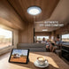 Interior of a modern RV with family inside, featuring a tablet and coffee on a table.