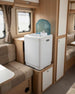 Portable washing machine in a compact living space with wooden paneling and seating.