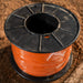 Spool of orange cable on a wooden surface