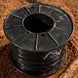 Black spool of wire on a wooden surface
