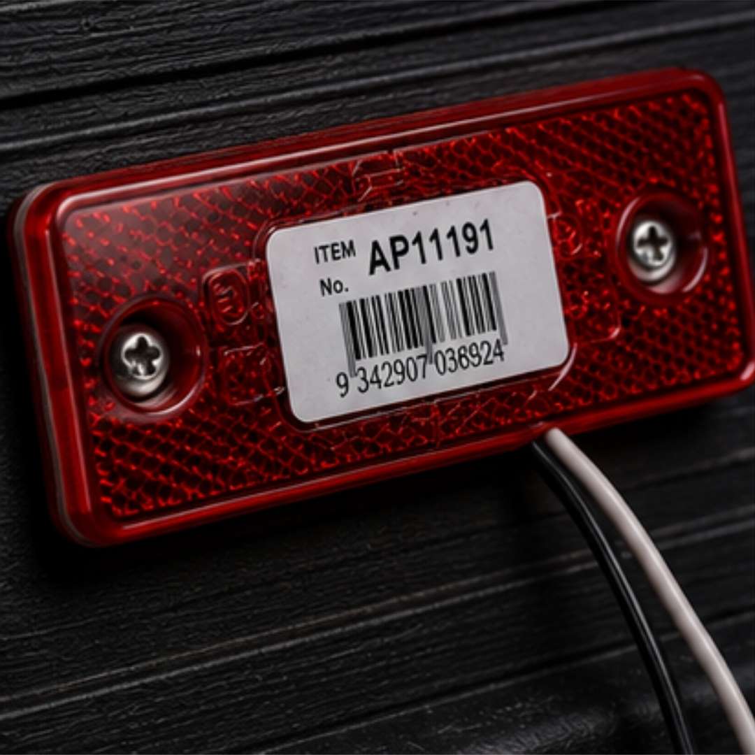 Red reflective label with barcode and text on a dark background