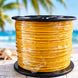 Spool of yellow cable on a wooden surface with a blurred beach background