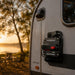 Close-up of a waterproof switch on a vehicle with a sunset and trees in the background